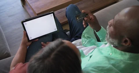 Diverse couple sitting on couch at home, blank tablet causing man angling credit Stock Footage 341736445