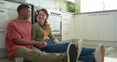 Diverse couple sitting kitchen holding hands, man showing palm explaining as Video stock 344850864