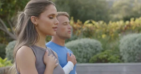 Diverse couple standing side by side placing hands over chest breathing slowly Vídeo Stock 337541553