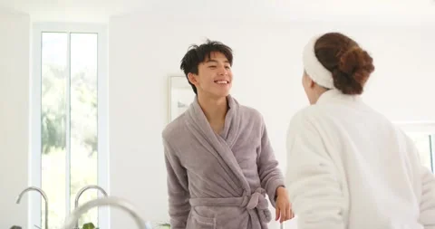 Diverse couple standing at vanity mirror, man glancing at woman, inspecting Stock Footage 335625590
