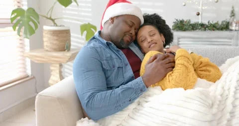Diverse couple stirring under blanket on sofa following slow camera pan, turning Stock Footage 336483830
