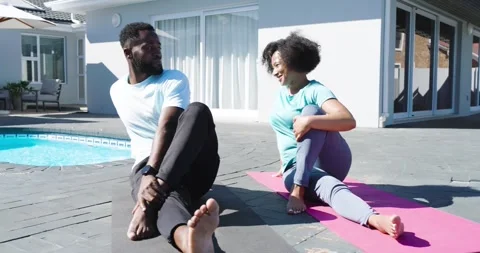 Diverse couple unrolling mats on poolside patio twisting, folding balancing boat Stock Footage 337159415