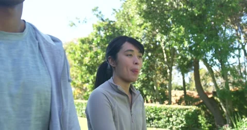 Diverse couple walking through sunny park, stretching arms for exercise and Stock Footage 339497026