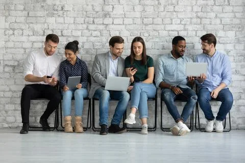 Diverse couples of millennial gadget users sharing content on tablet Stock Photos