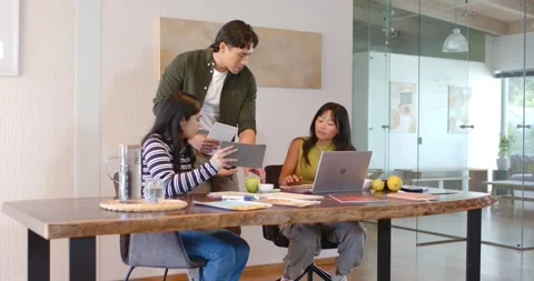 Diverse coworkers collaborating at office table, man presenting papers, apple Stock Footage 335895836