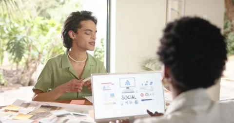 Diverse coworkers exchanging sticky notes at desk refining social graphics Stock Footage 341664863