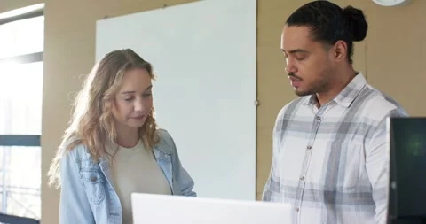 Diverse coworkers hearing initial remarks leaning forward and pointing at laptop Stock Footage 339413967