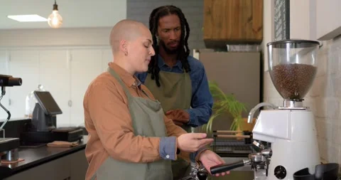 Diverse coworkers pulling lever on grinder, filling portafilter and training at Stock Footage 340968937