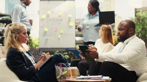 Diverse coworkers sharing notes beside laptop during outdoor meeting Stock Footage 338383417