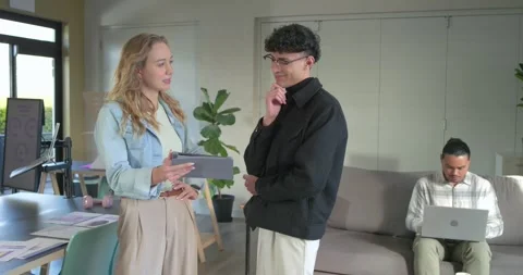 Diverse coworkers sharing tablet screen, urging colleague joining and Stock Footage 341393367