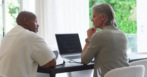 Diverse coworkers spotting code, gesturing and typing on laptop while reviewing Stock Footage 336569657