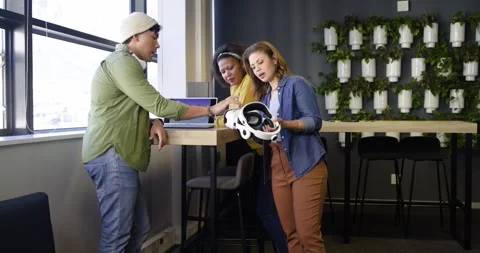 Diverse coworkers tapping screen, discussing data and inspecting VR headset at Stock Footage 337159662