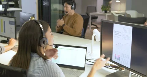 Diverse coworkers testing headset mic, discussing data, signing numbers for Stock Footage 335986223