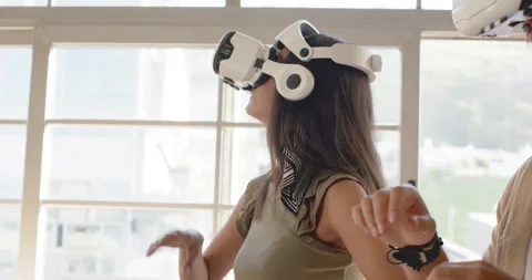 Diverse coworkers testing VR in loft, woman in olive top donning white headsets, Stock Footage 339983509