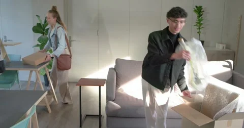 Diverse coworkers unpacking and assembling gold lamp and monitor riser after box Stock Footage 336715526
