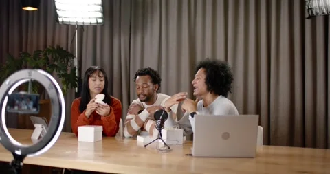 Diverse creators at studio, woman opening box, passing white device near ring Stock Footage 345590300