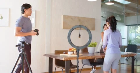 Diverse crew at table arranging props as man checking DSLR and ring light 스톡 동영상 335906968