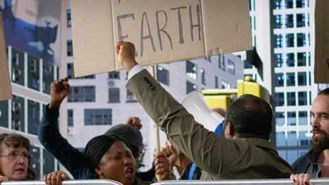 Diverse crowd of activists marching in a climate protest with banners Stock Photos