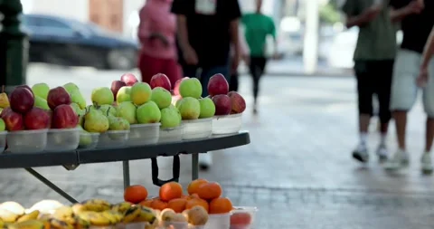 Diverse crowd walking amid rising traffic, passing fruit stall with basketball Stock Footage 339162311