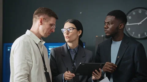 Diverse Cybersecurity Team Discussing Data on Digital Tablet Stock Footage 346813929