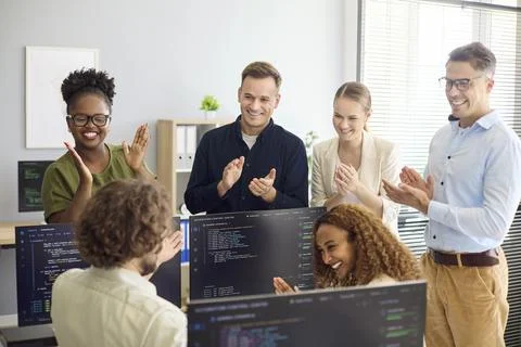 Diverse developer team applauding successful code release in modern office Fotos Stock
