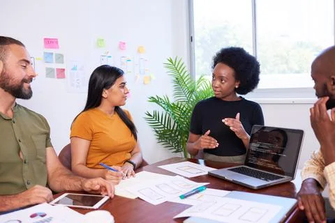 Diverse development team discusses code during code review meeting, programming Foto stock