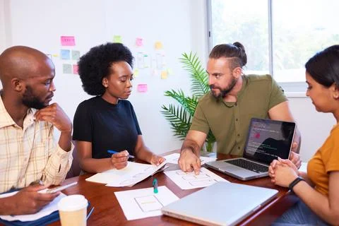 Diverse development team discusses code during code review meeting, programming Stock Photos