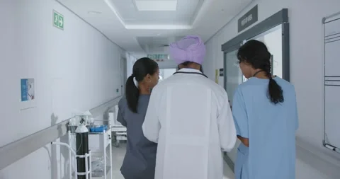 Diverse doctors and nurse talking and walking through corridor at hospital, in Stock Footage 339556440