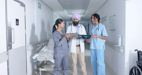 Diverse doctors and nurse using tablet and walking through corridor at hospital, Stock Footage 335568435