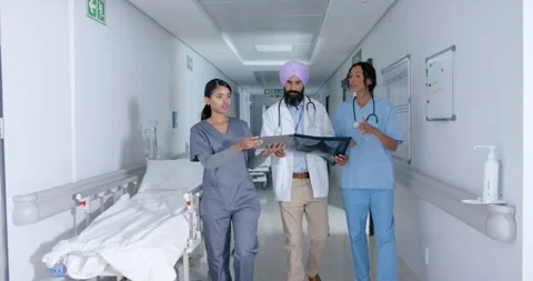 Diverse doctors and nurse using tablet and walking through corridor at hospital, Stock Footage 345213541