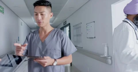 Diverse doctors and nurses using tablets and walking through corridor at Stock Footage 340256513