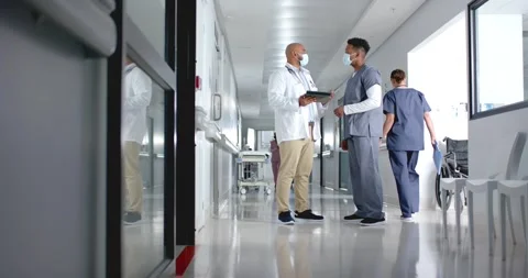 Diverse doctors discussing work and using tablet in corridor at hospital, slow Stock Footage 335198425