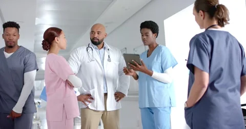 Diverse doctors discussing work and using tablet in corridor at hospital, slow Stock Footage 340979530