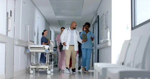 Diverse doctors using tablet and walking in corridor at hospital, slow motion Stock Footage 335985478