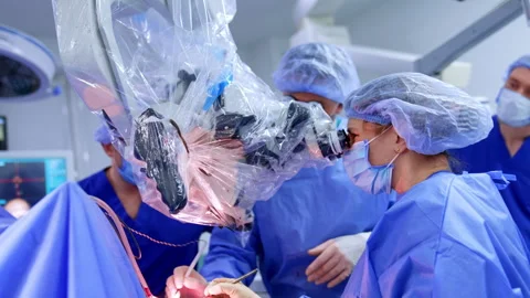 Diverse doctors work at neurosurgery looking at microscope Stock Footage 309406393
