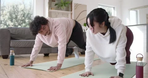 Diverse duo smiling, doing knee drives on mats, kneeling hand-slapping, Video stock 345090181