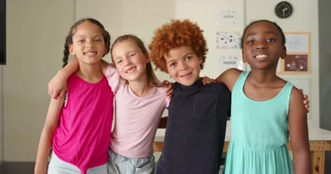 Diverse elementary children posing arm-in-arm in classroom by whiteboard, Stock Footage 341320312
