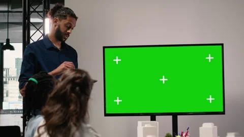 Diverse engineering staff study zoning regulations next to green screen on TV Stock Footage 316641273