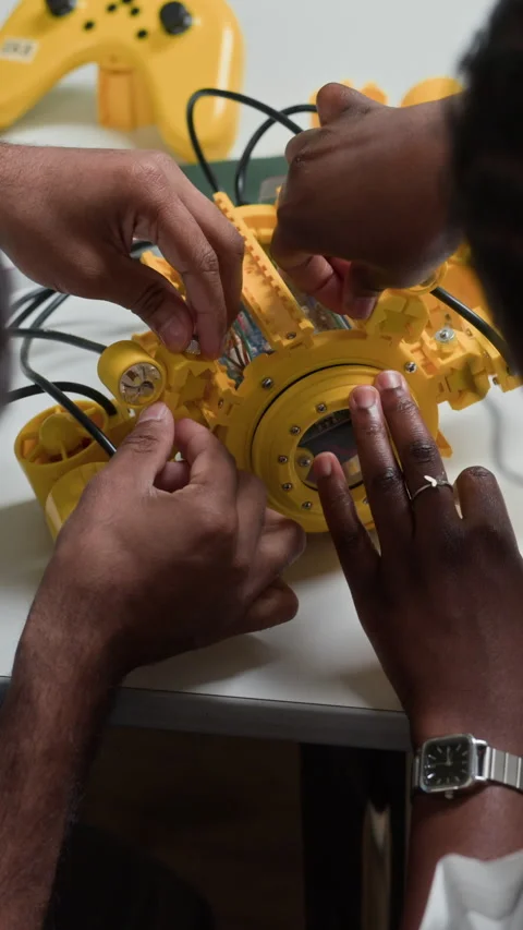Diverse Engineers Collaborating on Building Yellow Robot Prototype Stock Footage 343503642