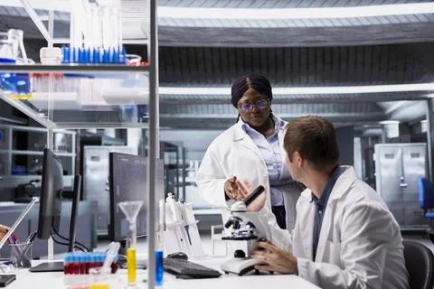 Diverse experts examining microscope slide with laboratory tray Stock Photos