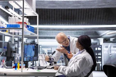 Diverse experts team at microscope analyze tissue on glass tray Stockfoto's
