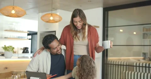 Diverse family sitting at kitchen table child reaching tablet man pointing with Stock Footage 338064483