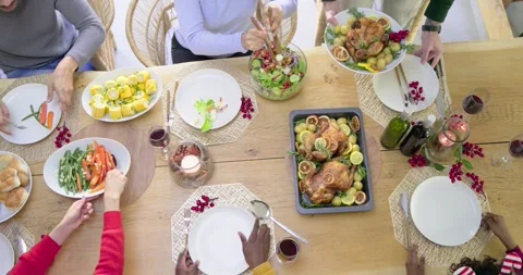 Diverse family starting dinner, serving roast chicken platter and salad with Stock Footage 339590722