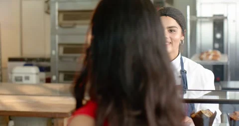 Diverse female baker in chef coat turning to customer entering, ordering Stock Footage 337294830