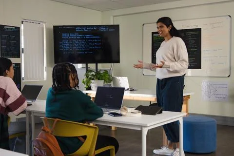 Diverse female class with Indian instructor teaching teenage students coding on Stock Photos