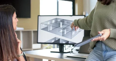 Diverse female coworkers using tablet while pointing floor plan on monitor at Stock Footage 336367448