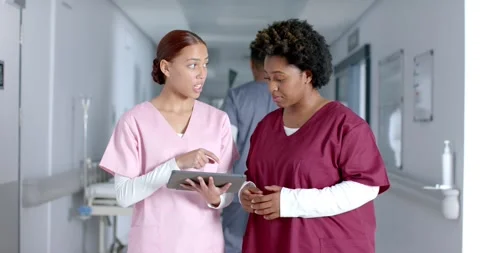 Diverse female doctors discussing work and using tablet in corridor, slow motion Stock Footage 345566721