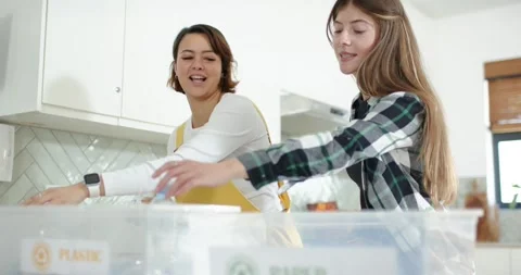Diverse female duo sorting recycling at counter, placing bottles in PLASTIC bin Stock Footage 341851933