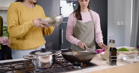 Diverse female friends chopping cabbage, passing oil, tossing wok, preparing Vidéo 344463537