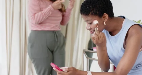 Diverse female friends getting ready at vanity, woman applying blush with brush, Stock Footage 336658447